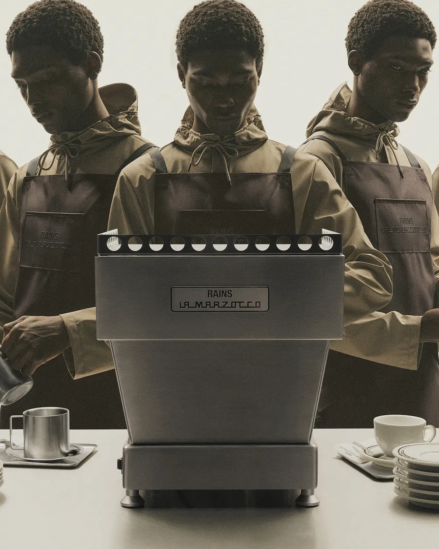 Baristas wearing the Rains and La Marzocco apron at a Linea Mini with a Rains plate